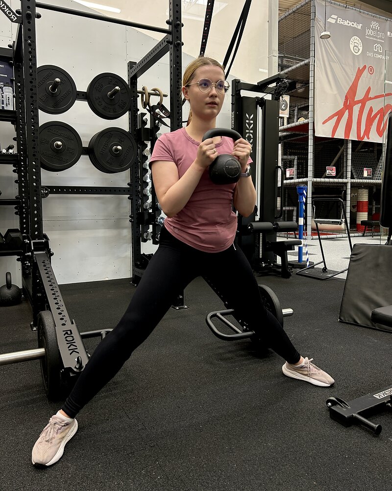 Kobieta wykonuje boczny wykrok z kettlebell